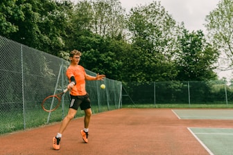 woman in black tank top playing tennis during daytime