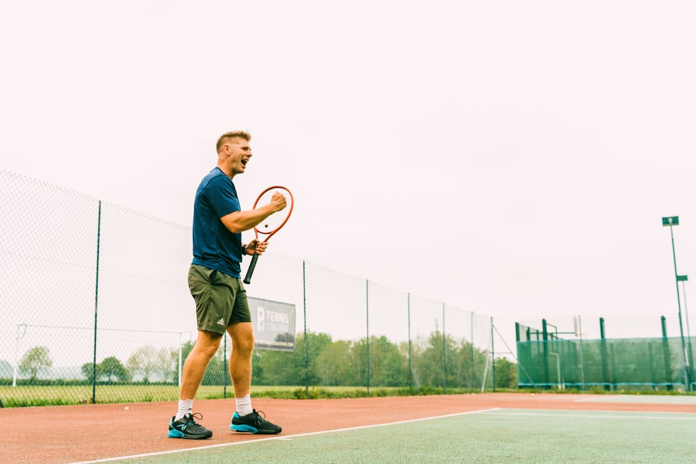 man in blue shirt and green shorts running on track field during daytime