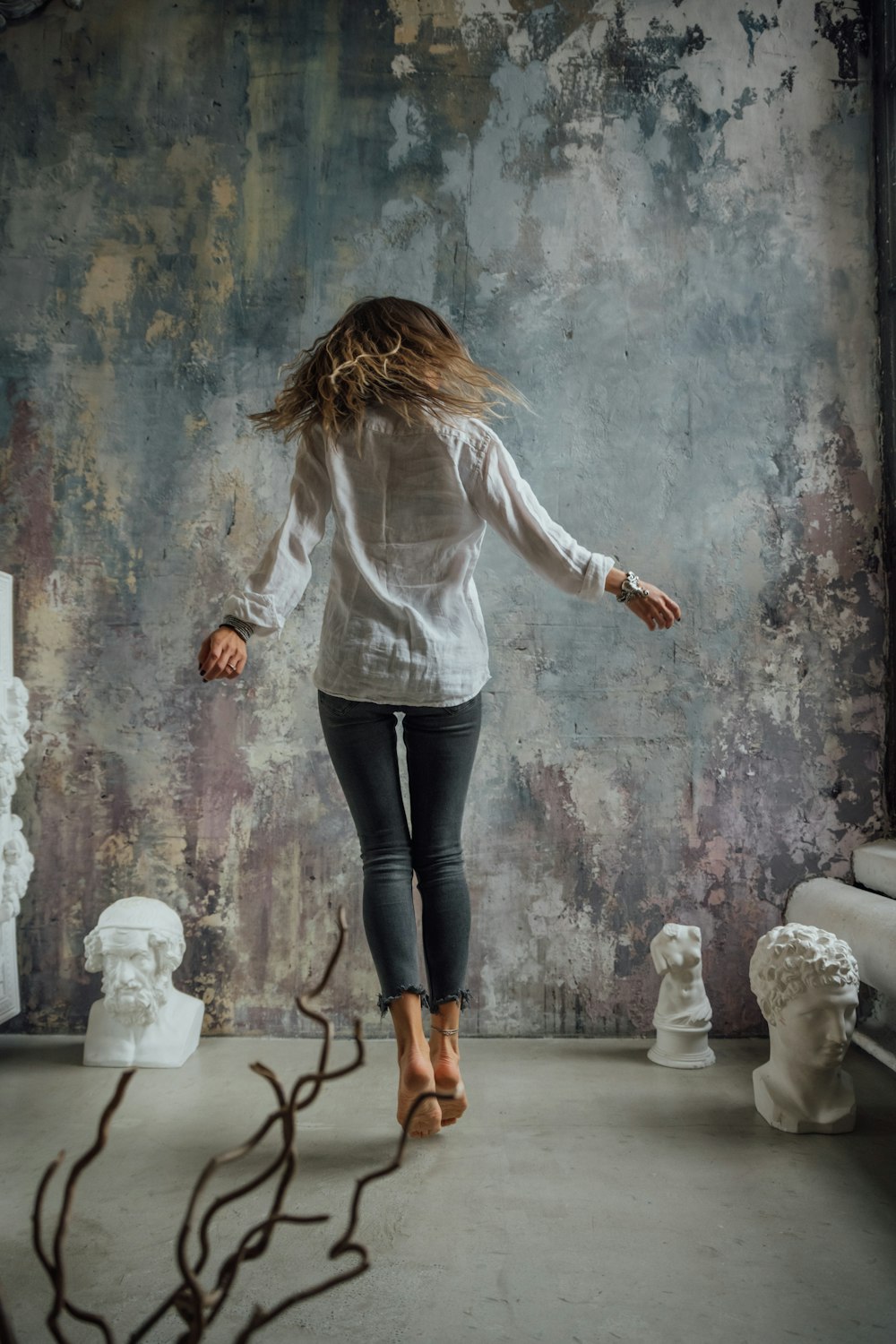 woman in white long sleeve shirt and black pants standing on gray concrete floor