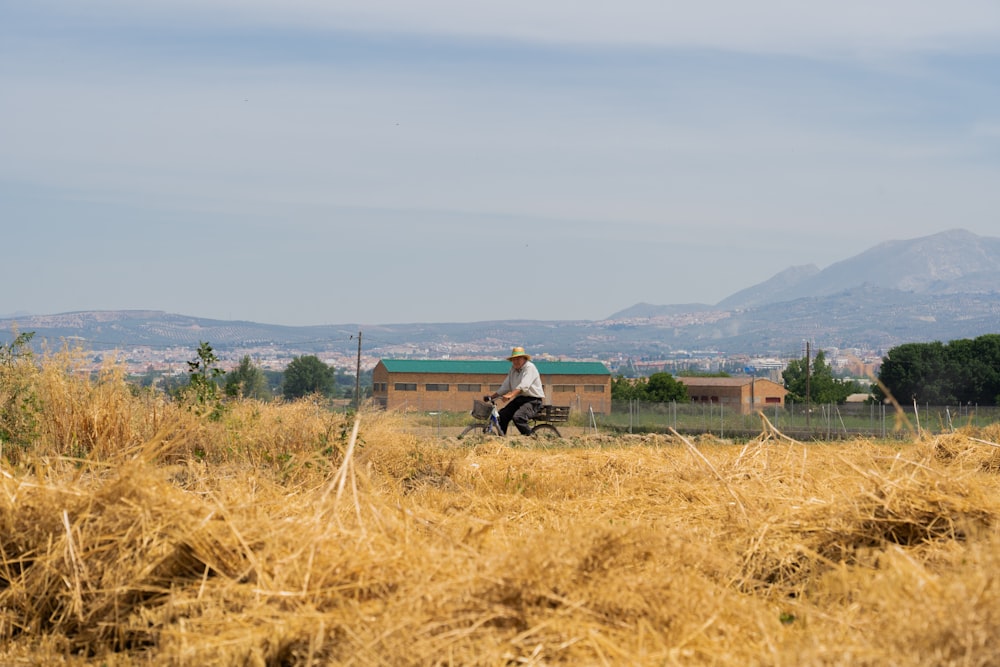 Hombre en chaqueta negra sentado en el campo de hierba marrón durante el día