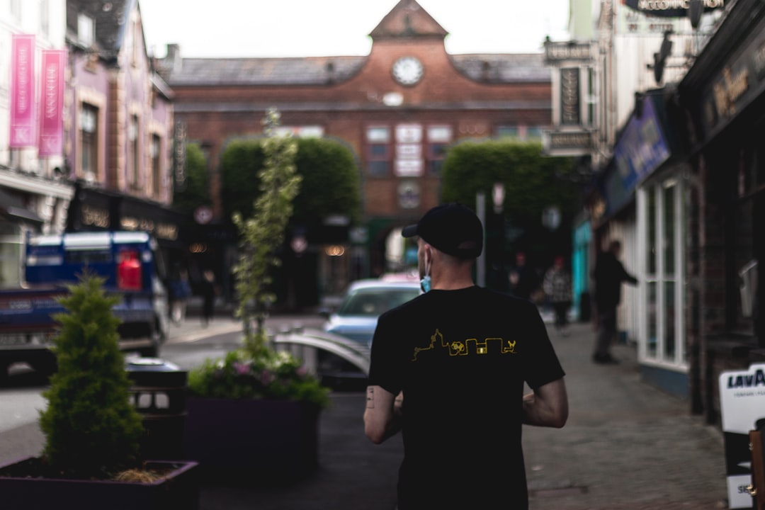 man in black crew neck t-shirt standing near green tree during daytime