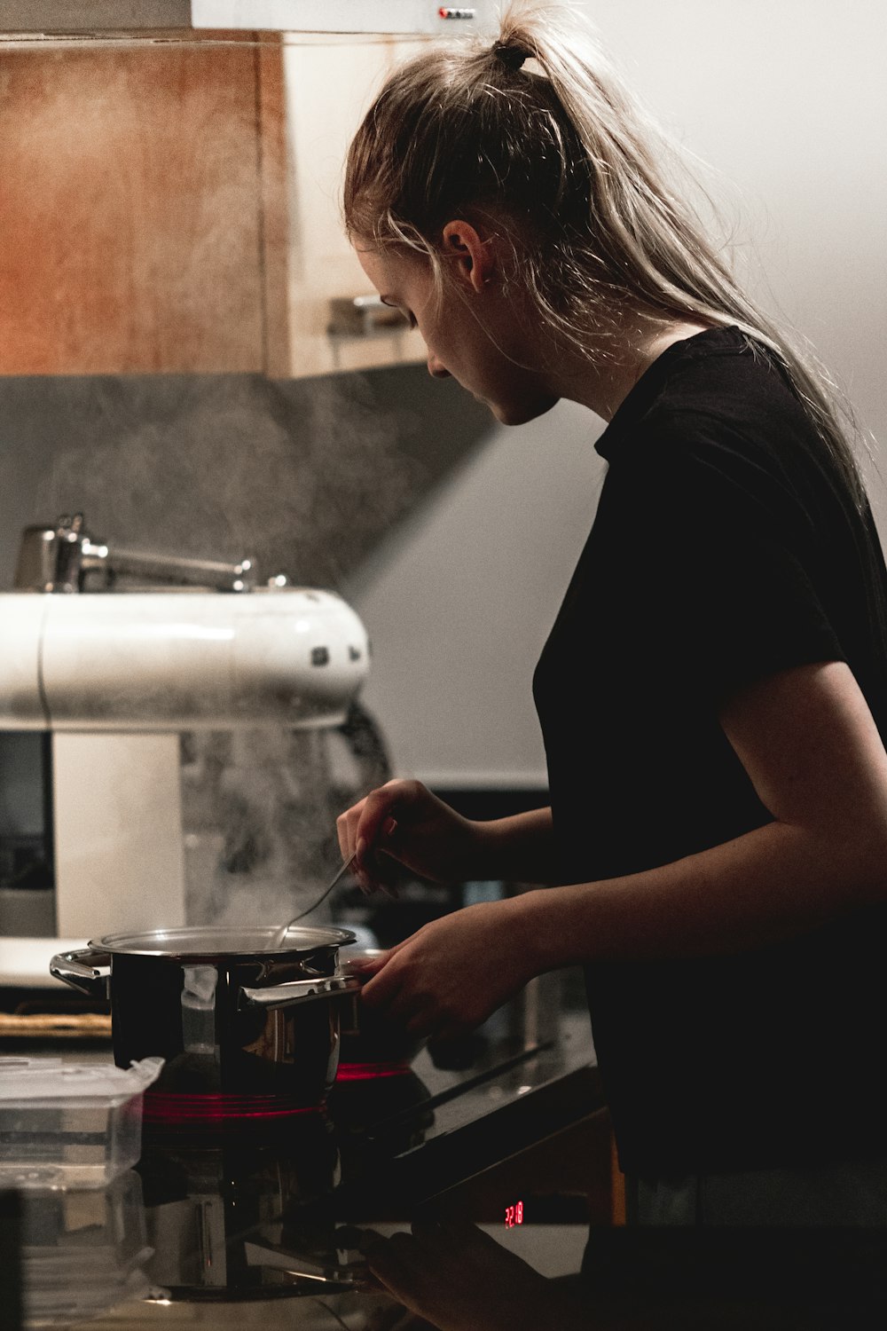 woman in black t-shirt pouring coffee on clear glass mug