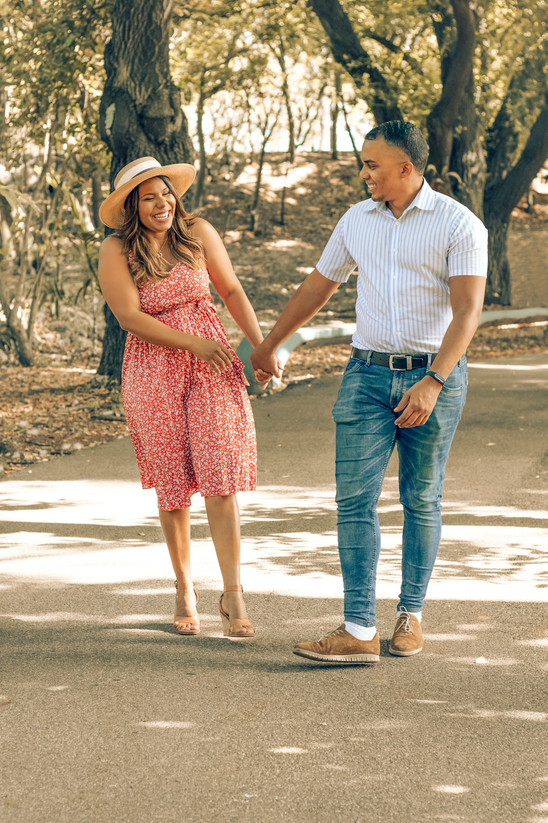 man in white polo shirt and woman in red sleeveless dress walking on gray sand during