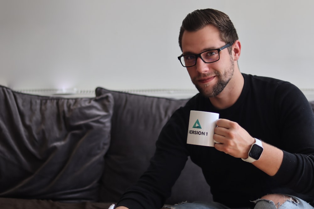 man in black long sleeve shirt holding white ceramic mug