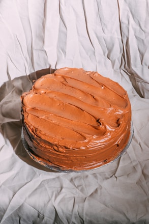 Close-up of a homemade cake with smooth, creamy frosting on the left side.