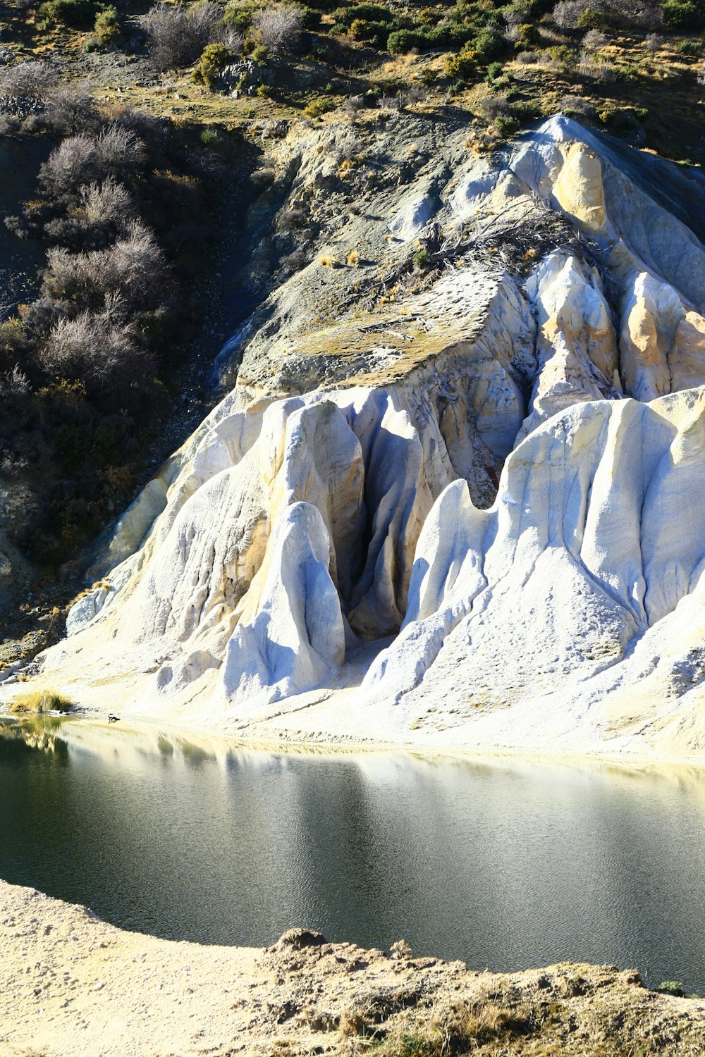 white and gray mountain near green trees and lake during daytime