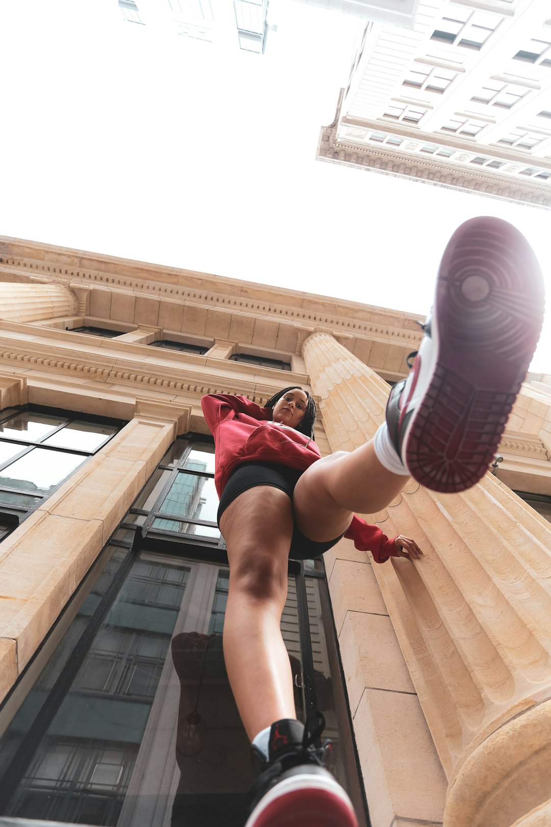 woman in red tank top and black and white striped shorts jumping on brown wooden stairs