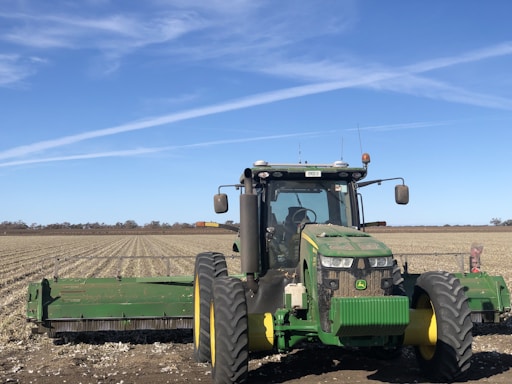 A farmer inspecting a modern tractor in a Libyan field under a clear sky