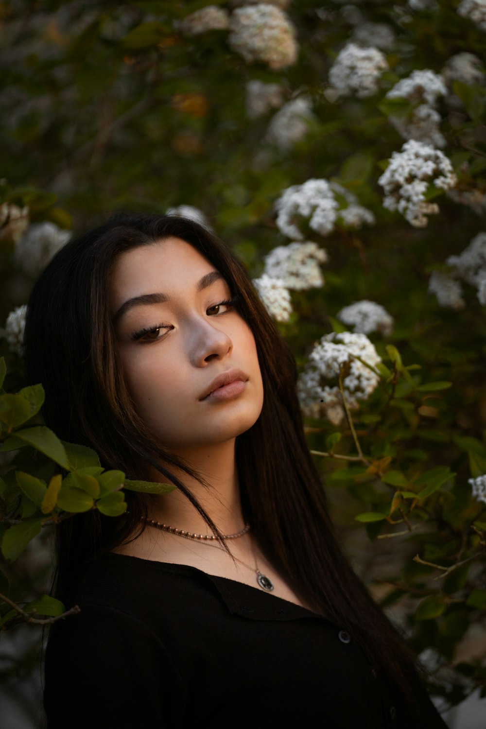 woman in black shirt standing under white flowers