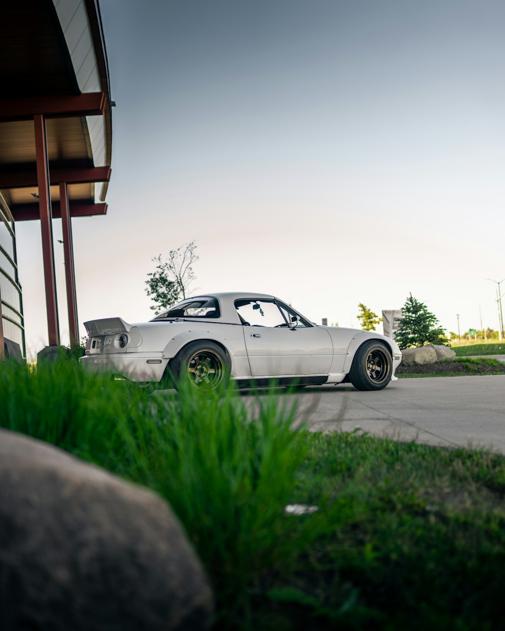 white coupe parked on gray concrete road during daytime