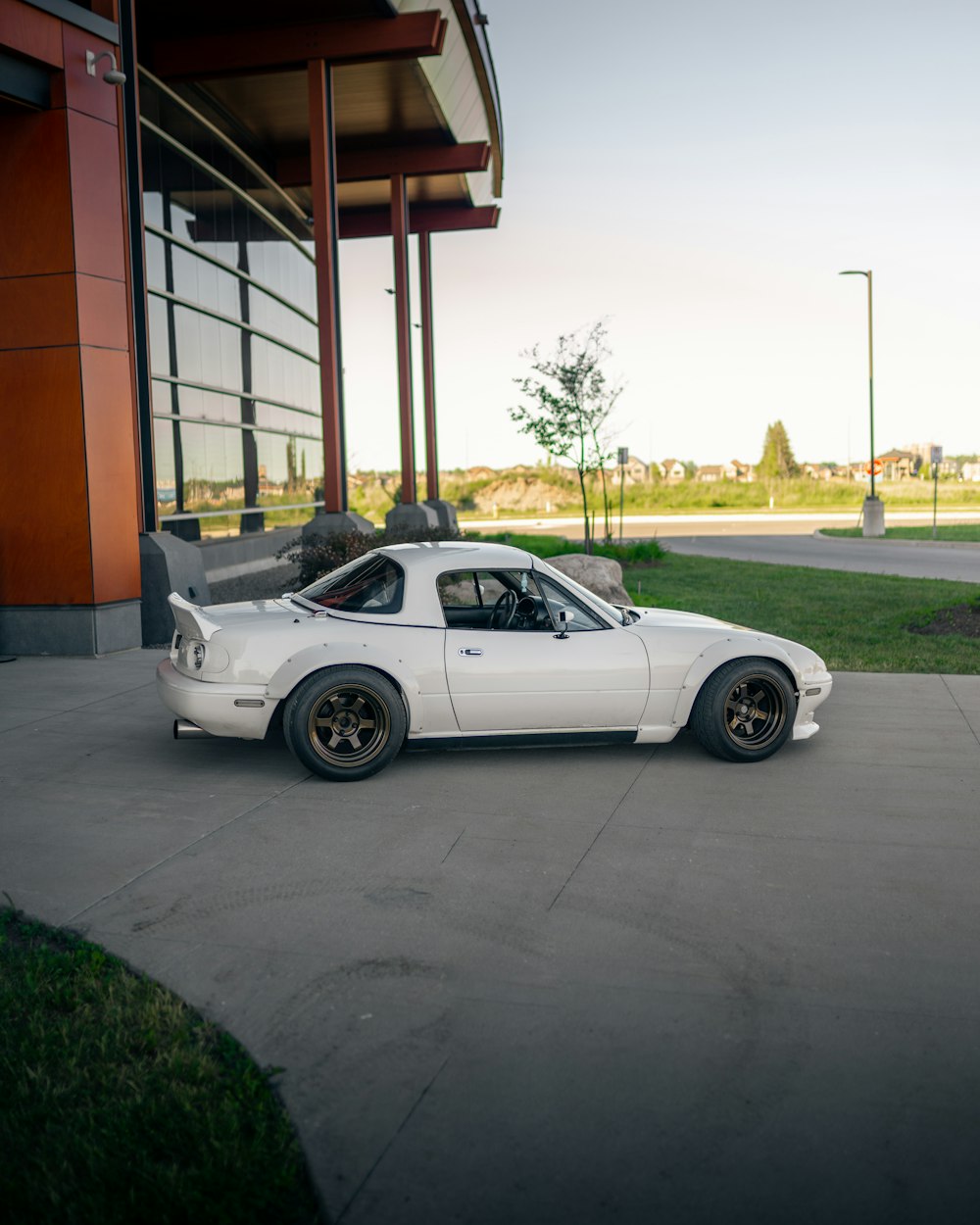 white coupe parked on gray concrete road during daytime