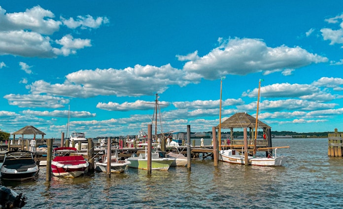boats on dock under blue sky and white clouds during daytime