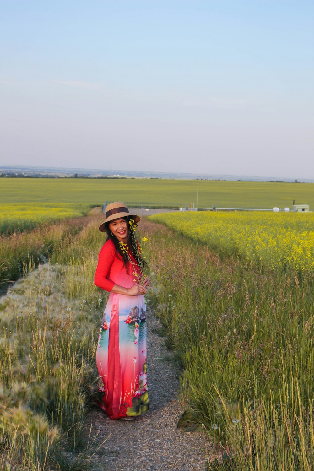 woman in red and white dress standing on green grass field during daytime