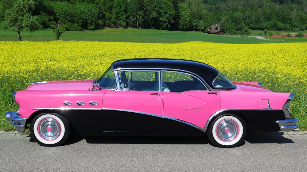 pink vintage car on green grass field during daytime