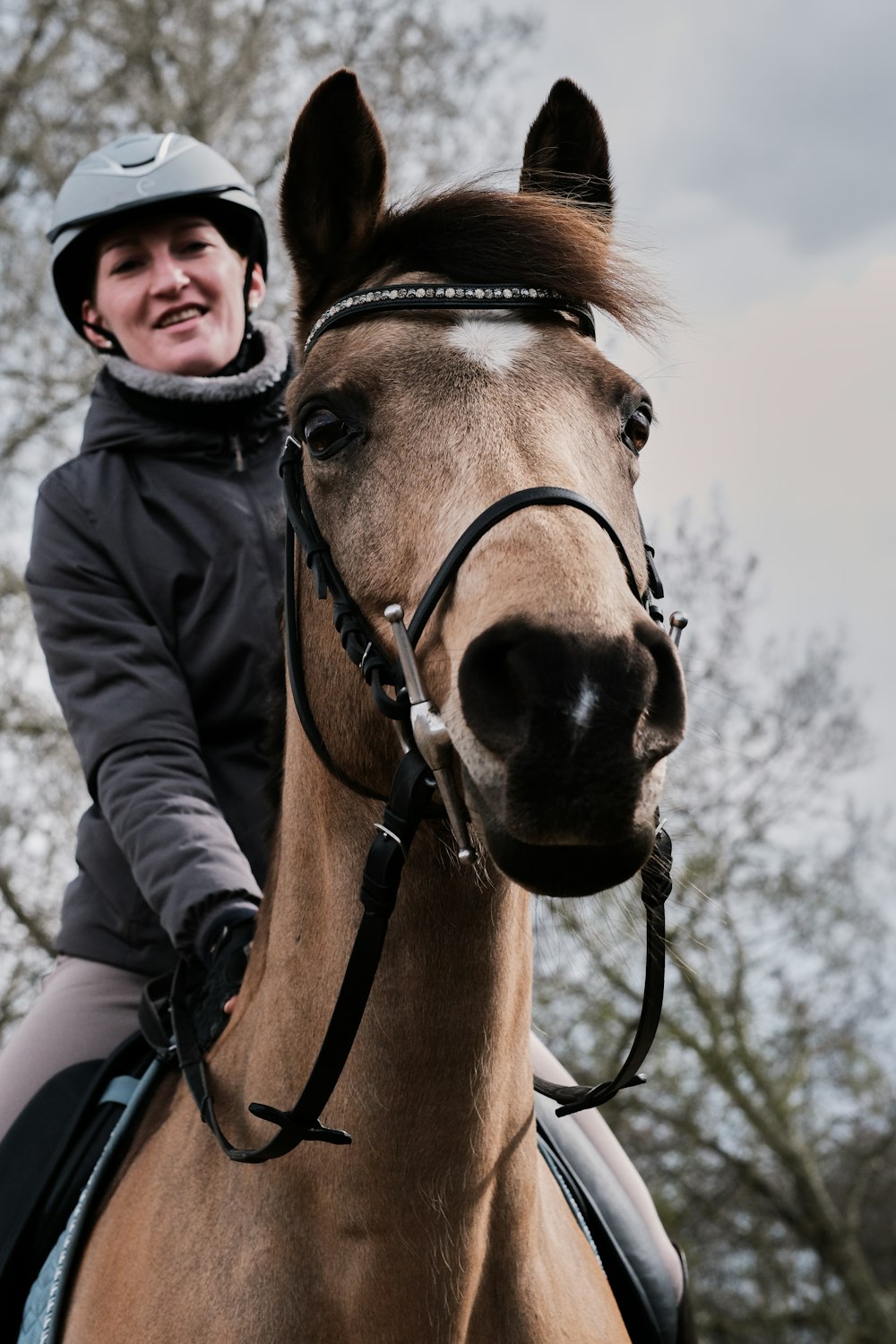 man in black leather jacket and black hat riding brown horse during daytime