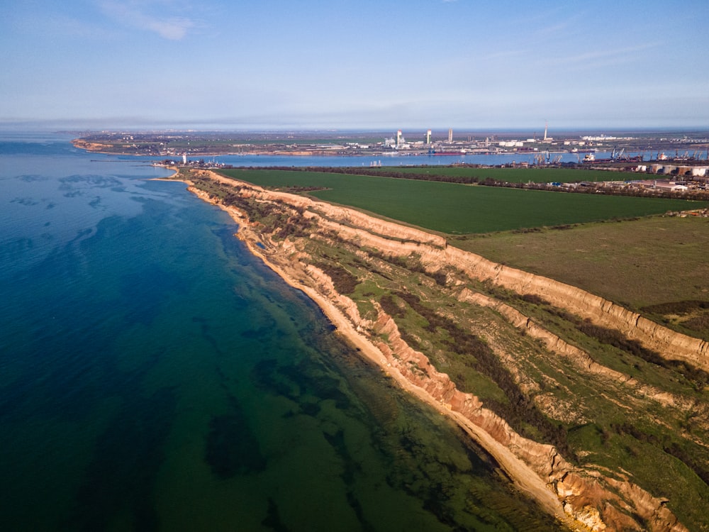 Vista aérea de un campo verde y marrón cerca del cuerpo de agua durante el día