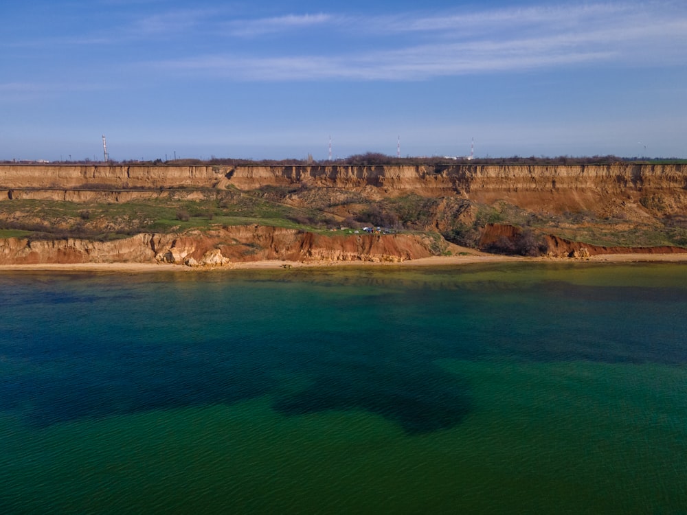 body of water near brown mountain under blue sky during daytime