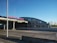 A modern building with the words 'BRATISLAVA JAROVCE' in red on the roof. The structure has a curved design and multiple windows, with a highway or road in the foreground and a clear blue sky. Trees line the horizon in the distance.