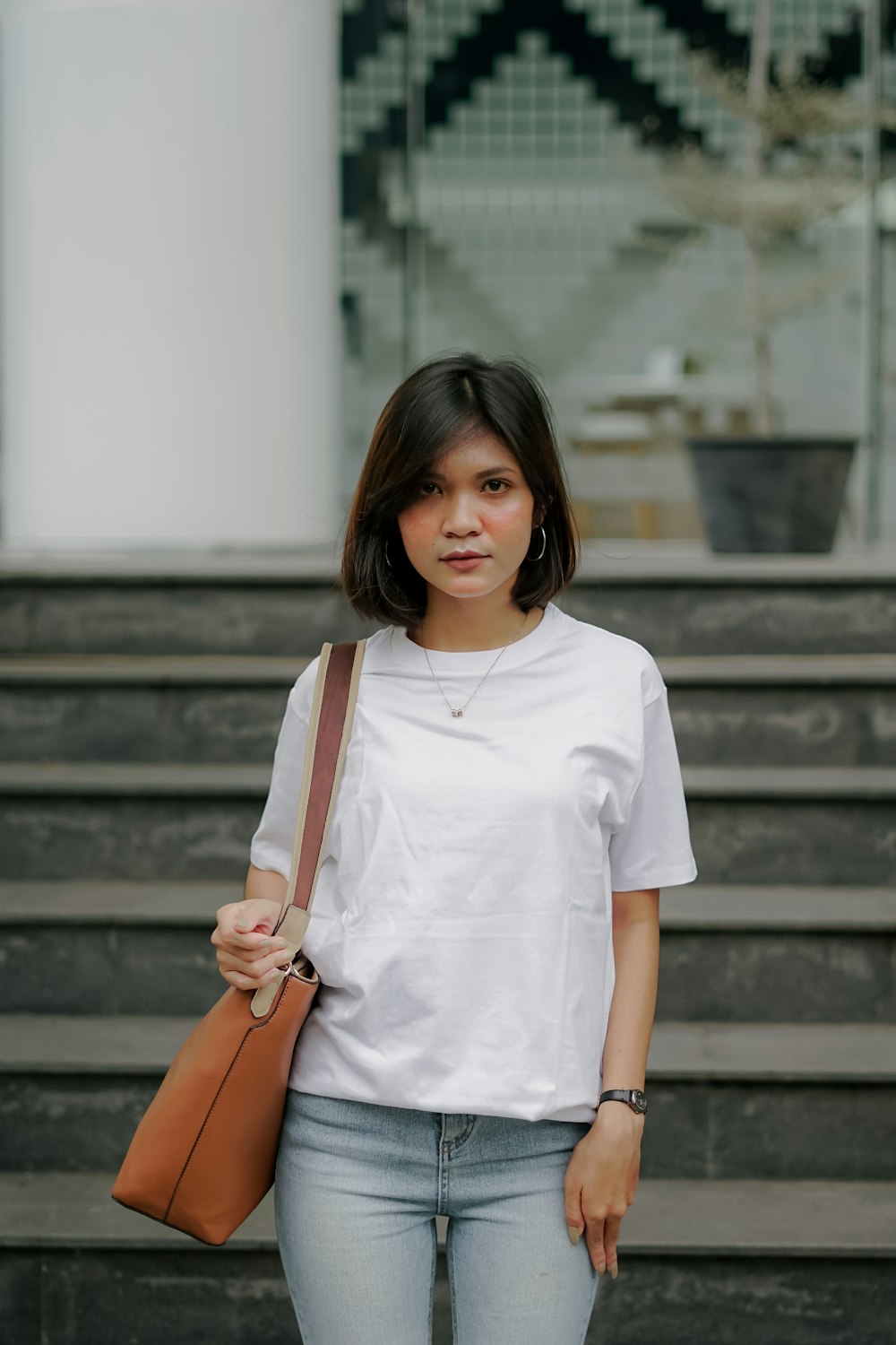 Femme en t-shirt à col rond blanc et sac à bandoulière en cuir marron