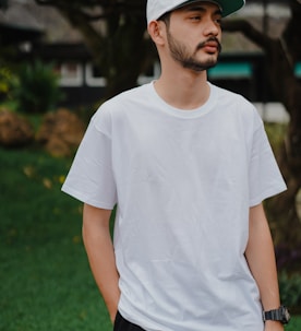 man in white crew neck t-shirt standing on green grass field during daytime