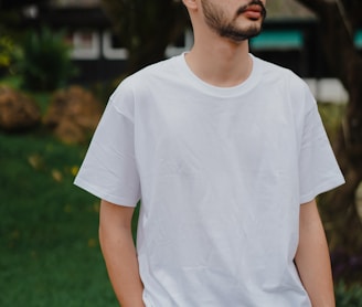 man in white crew neck t-shirt standing on green grass field during daytime