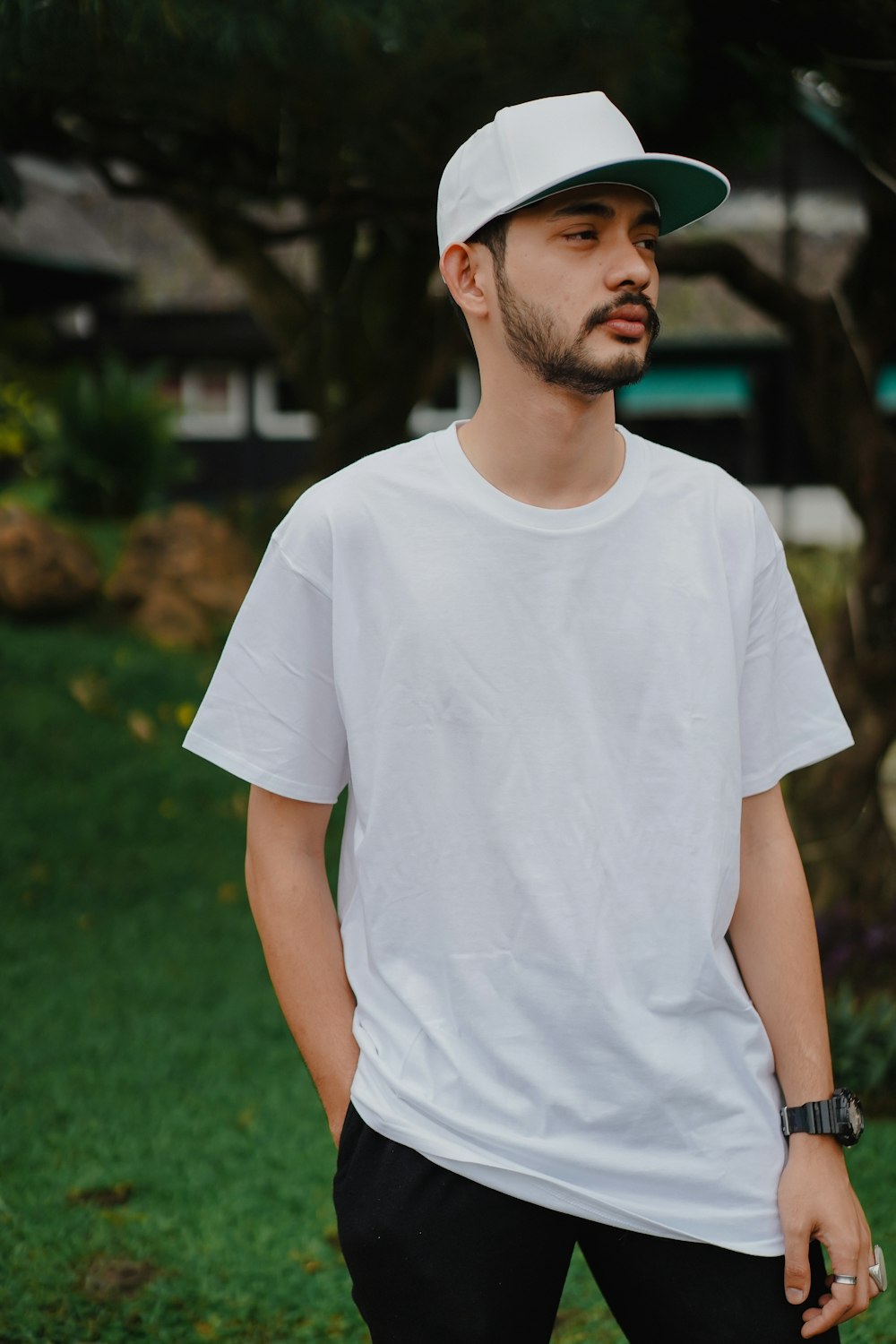 homme en t-shirt à col rond blanc debout sur le champ d’herbe verte pendant la journée