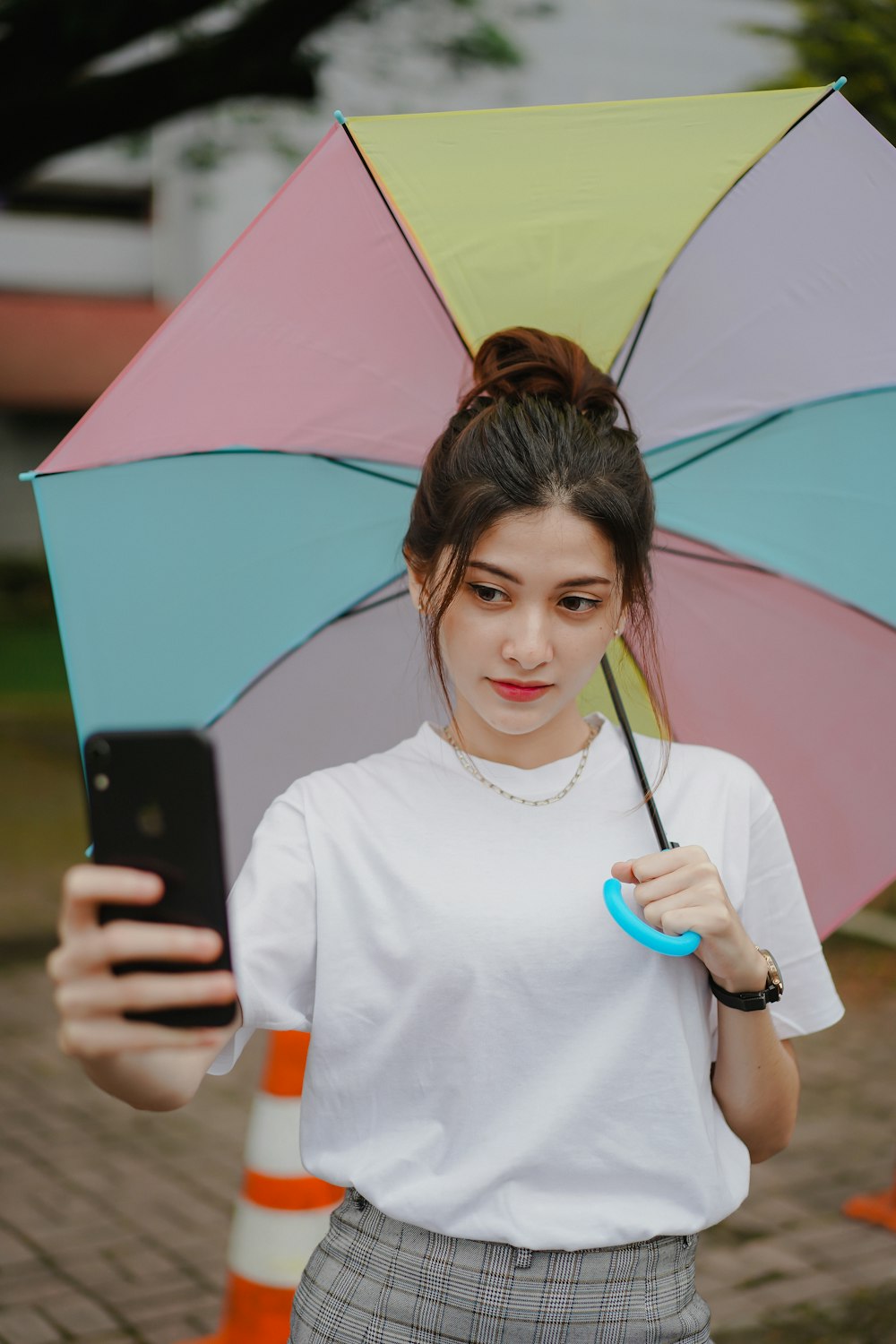 Mujer con camiseta blanca de cuello redondo sosteniendo un teléfono inteligente negro
