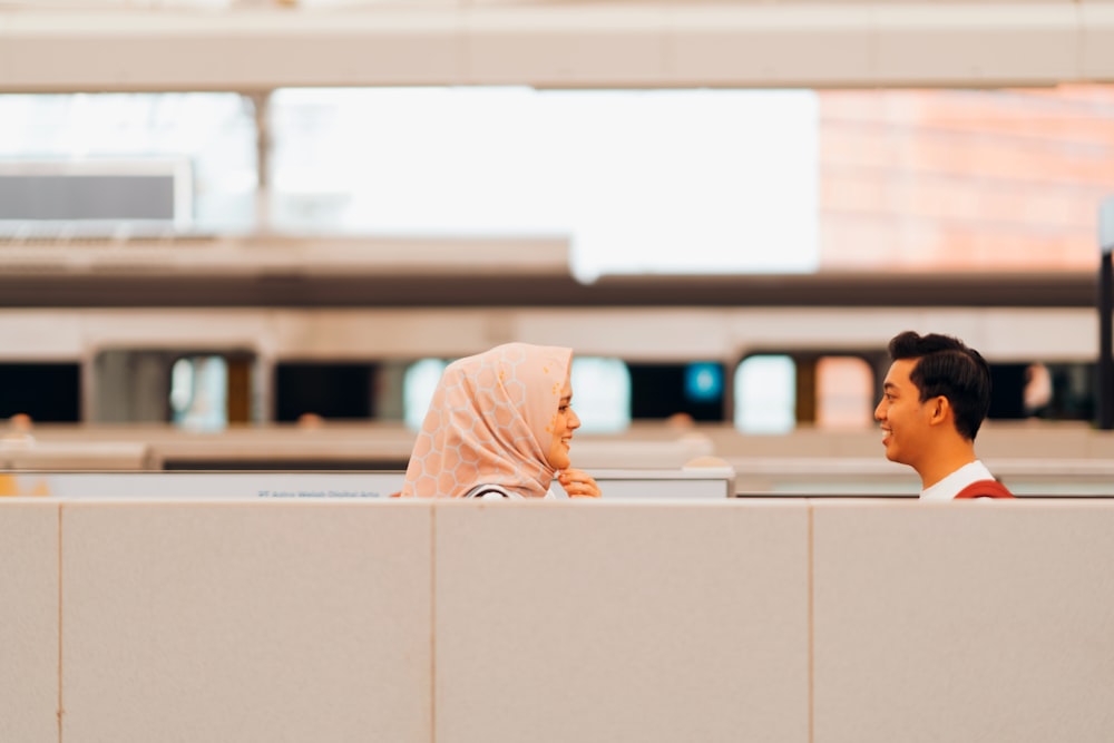 Woman wearing hijab at office talking to coworker