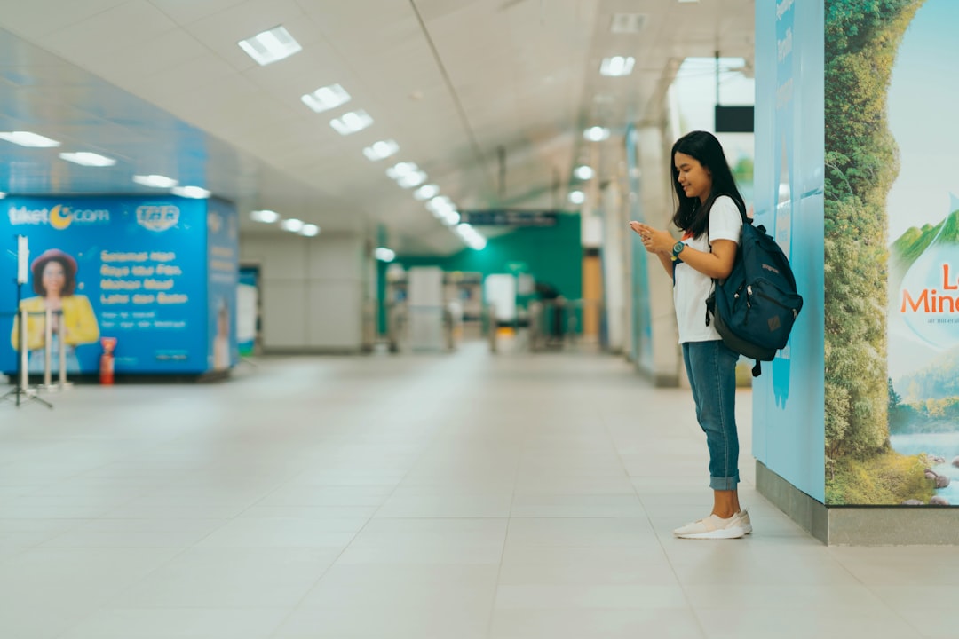 woman in black jacket and blue denim jeans standing on white floor tiles