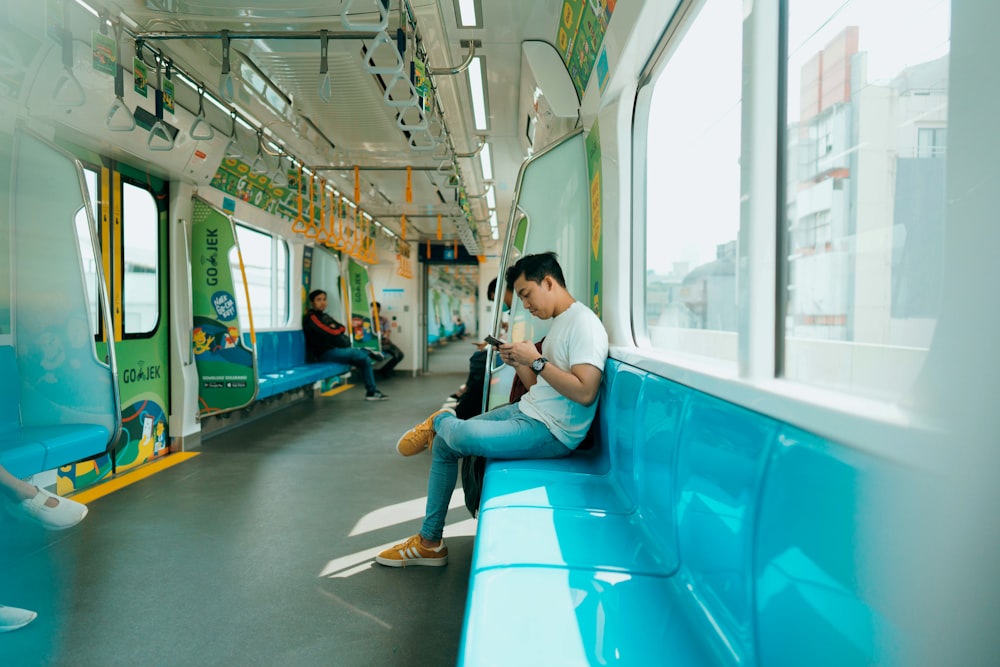 donna in camicia bianca che si siede sul sedile blu del treno