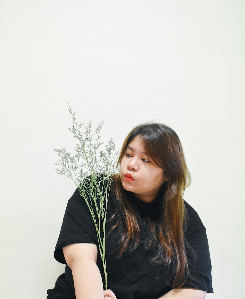 woman in black shirt standing beside green plant