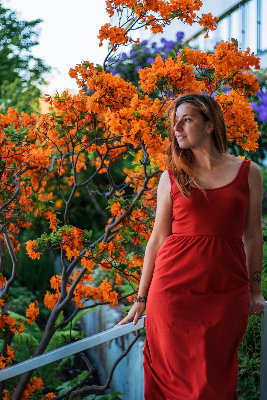 woman in red tank dress standing beside orange flowers