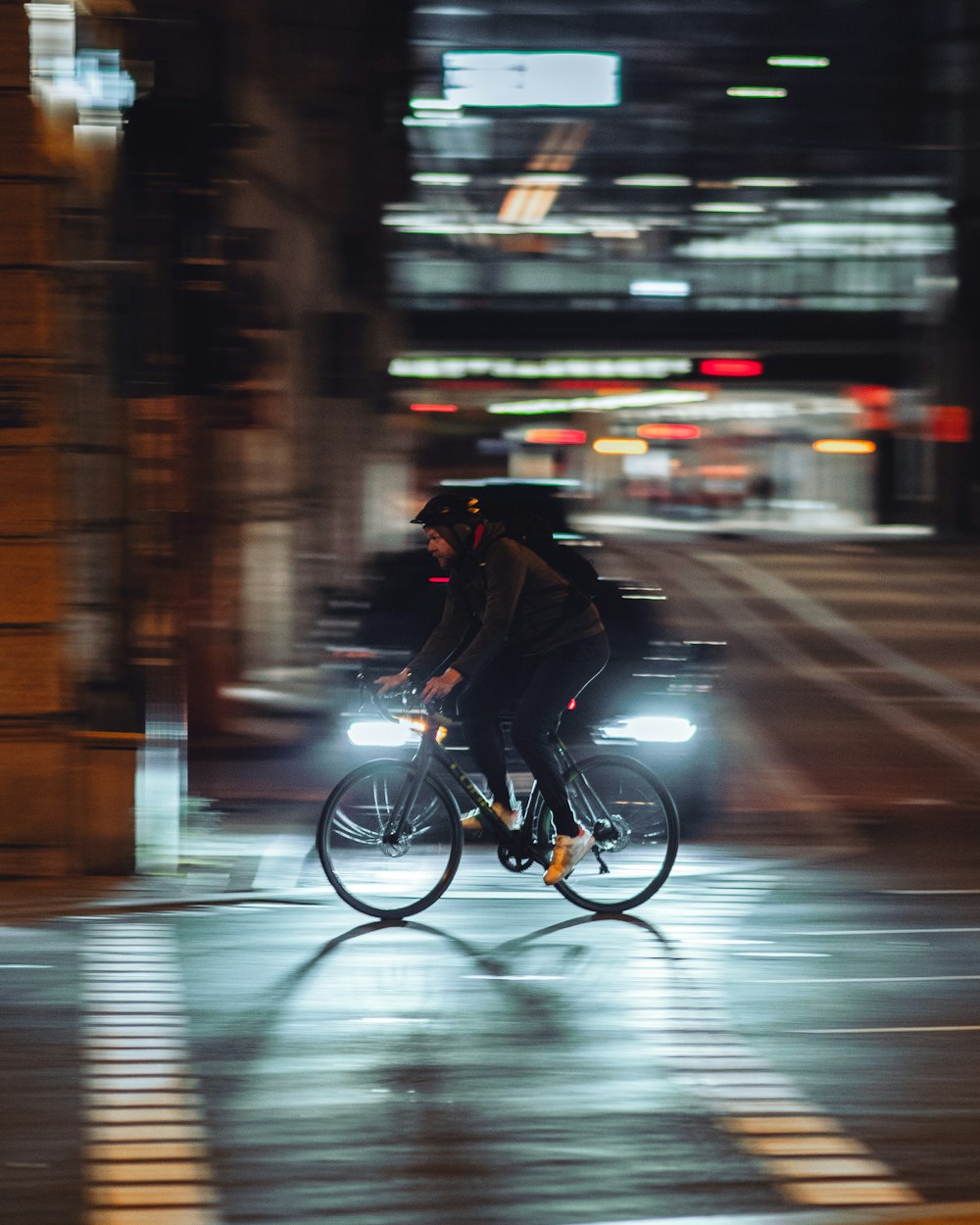 man in black jacket riding bicycle on road during night time