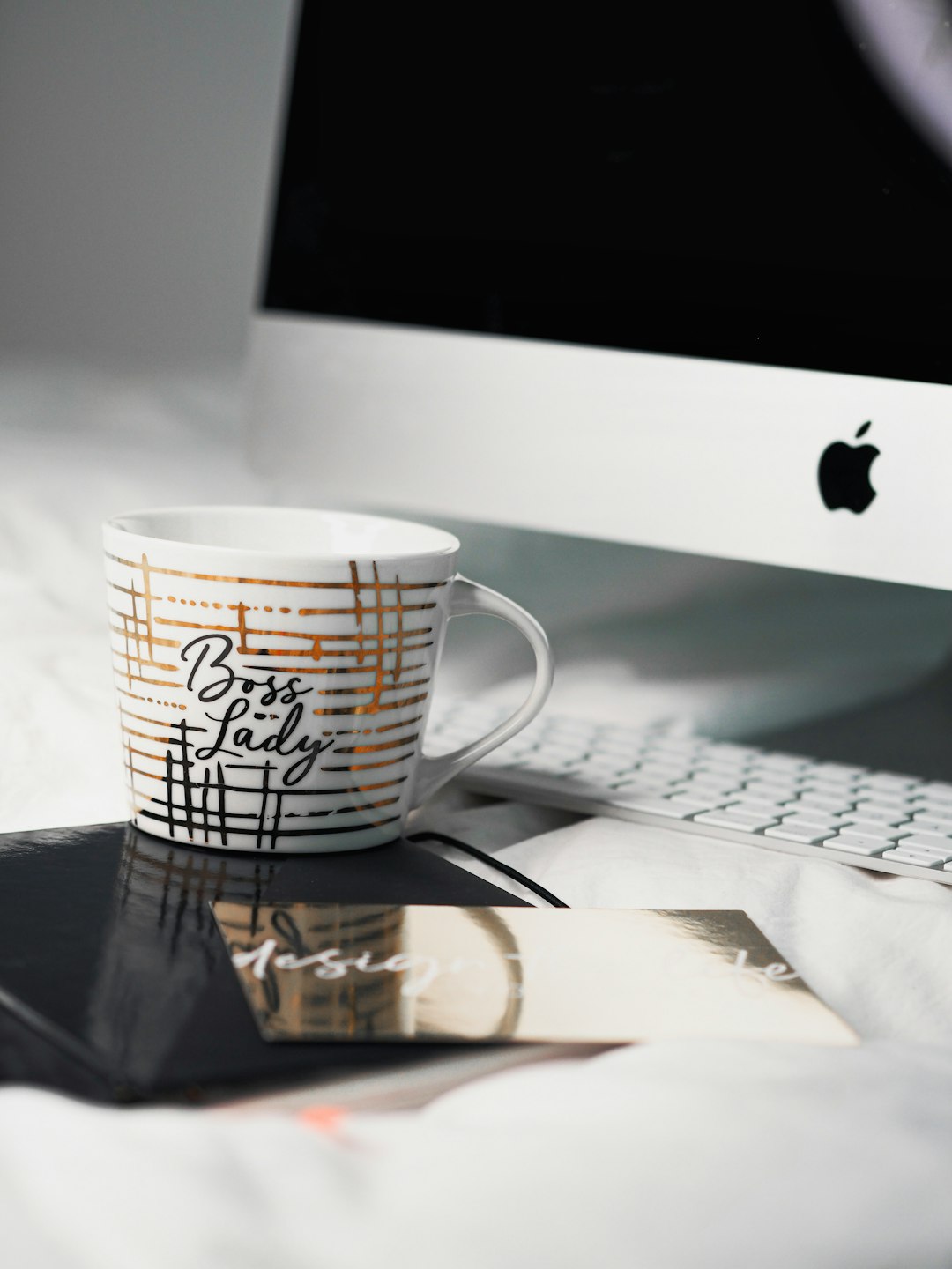 white and black ceramic mug beside silver imac