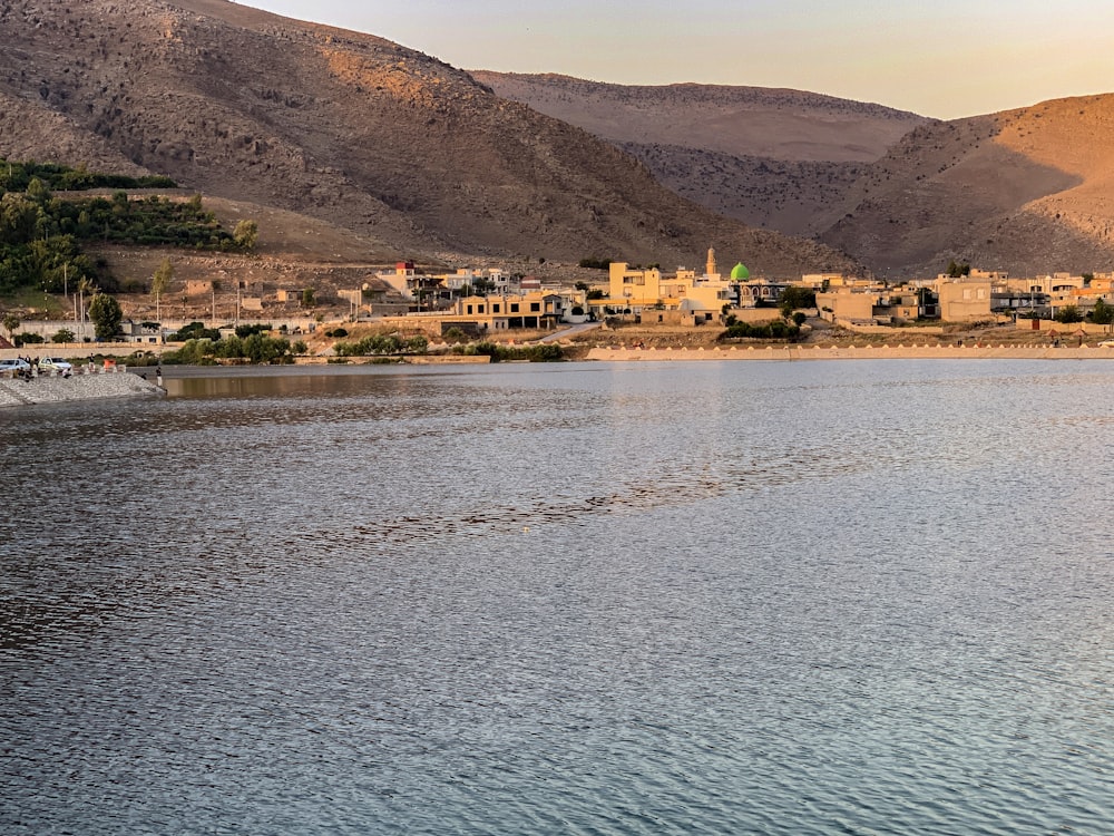 body of water near green trees and mountain during daytime