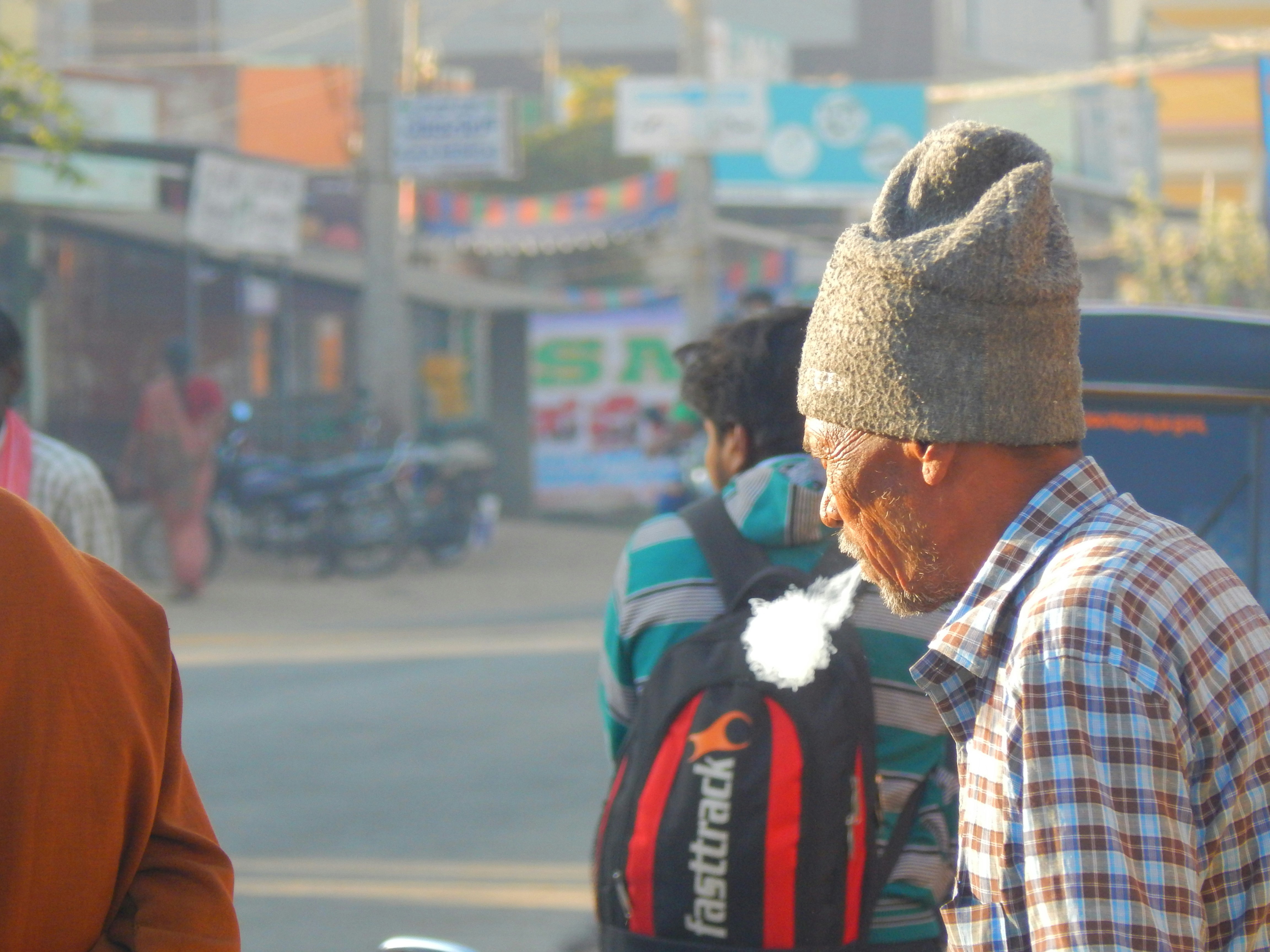 Homme en chemise à carreaux blanc, noir et rouge portant une casquette en tricot marron