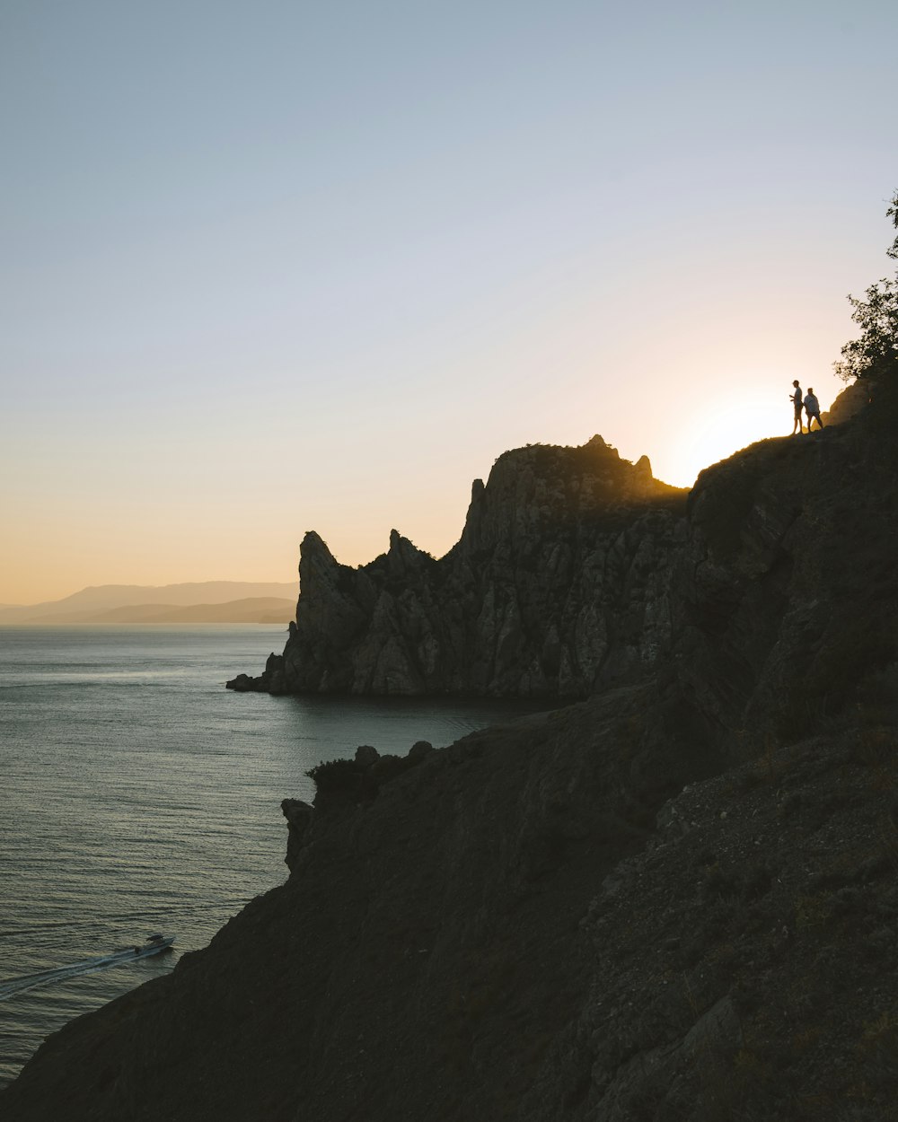 silhouette of mountain near body of water during sunset