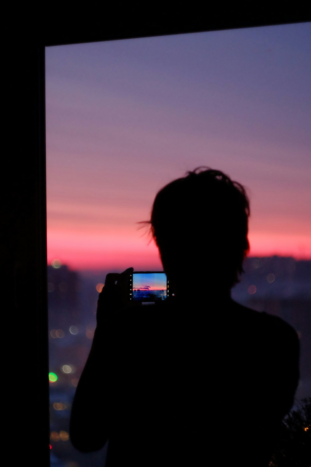 silhouette of man holding smartphone during sunset