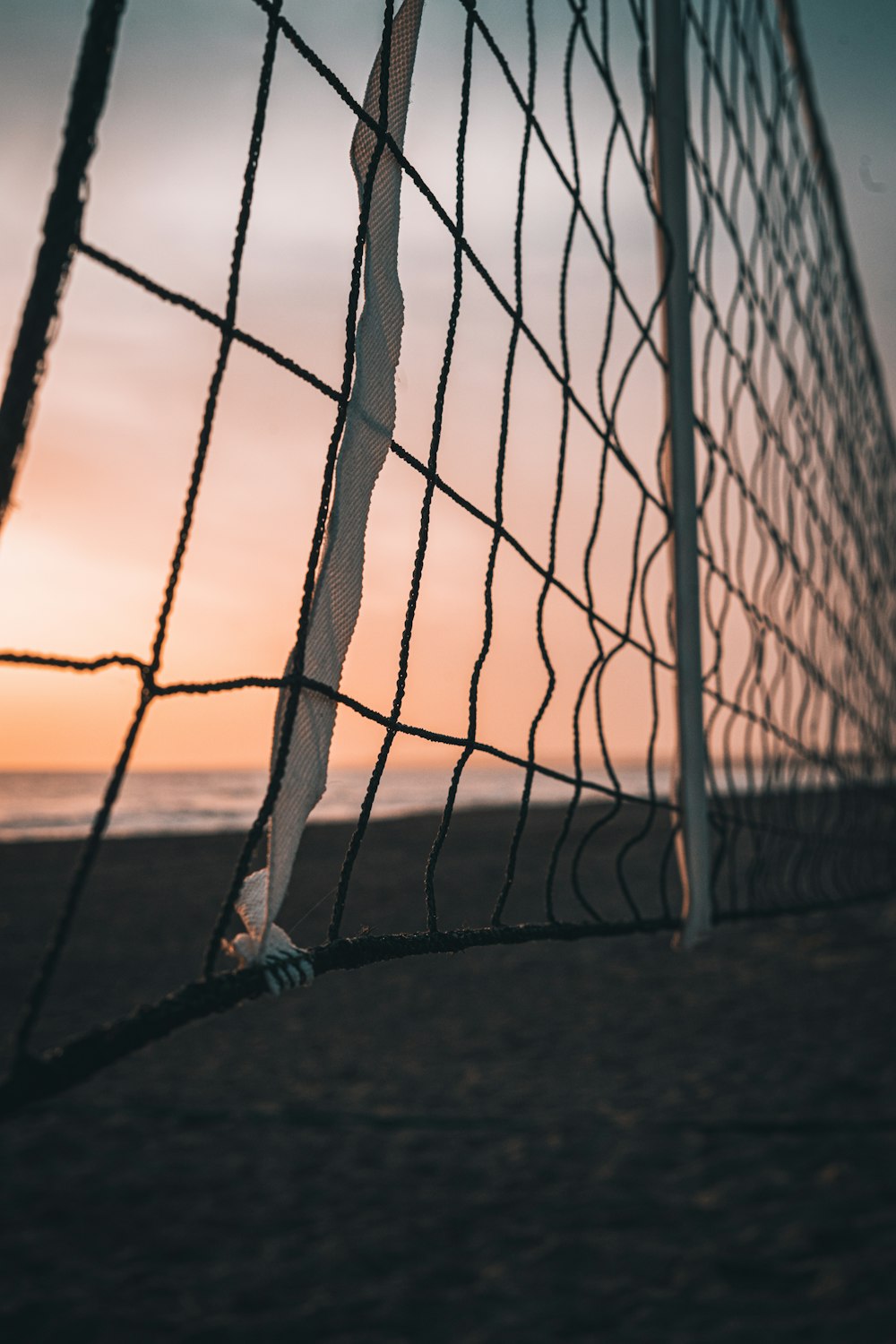 Schwarzer Metallzaun auf braunem Sand bei Sonnenuntergang