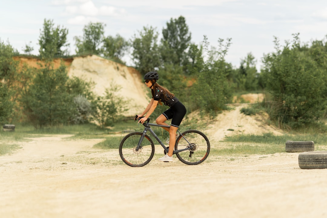 man in black shirt riding bicycle on dirt road during daytime