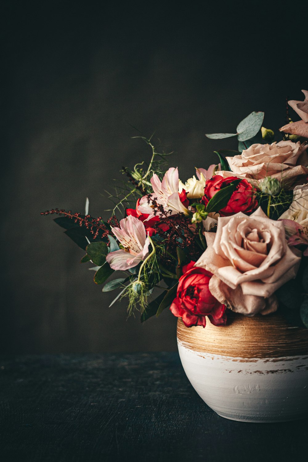 red and white roses in brown ceramic vase
