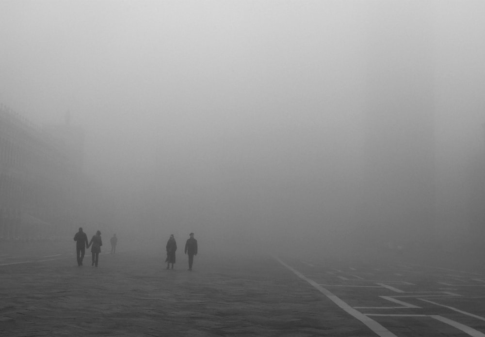 a group of people walking down a street in the fog