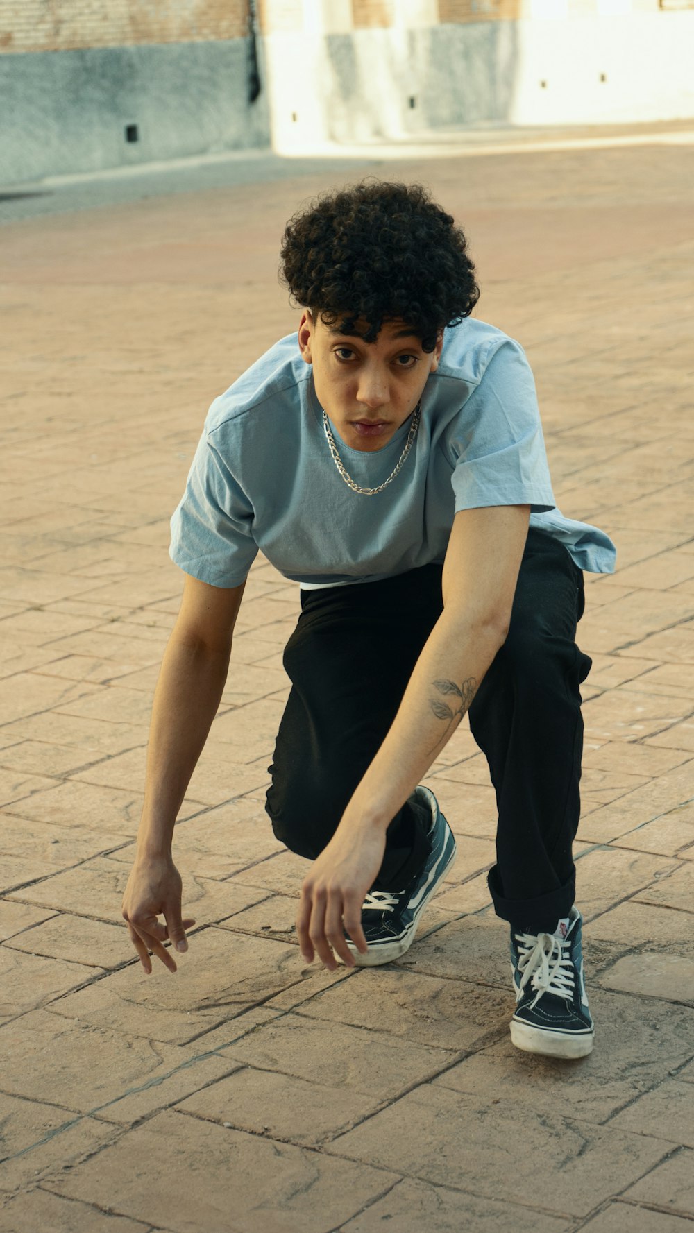 man in white crew neck t-shirt and black pants sitting on brown concrete floor during