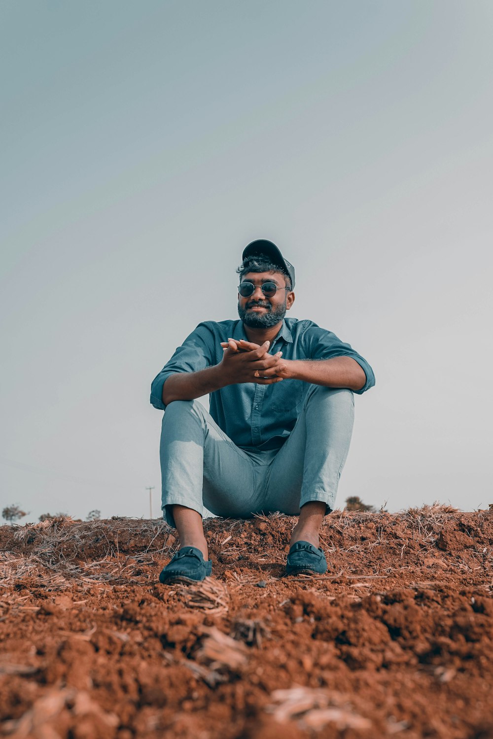 man in blue polo shirt sitting on brown rock during daytime