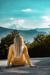 woman in orange long sleeve shirt standing near green trees during daytime