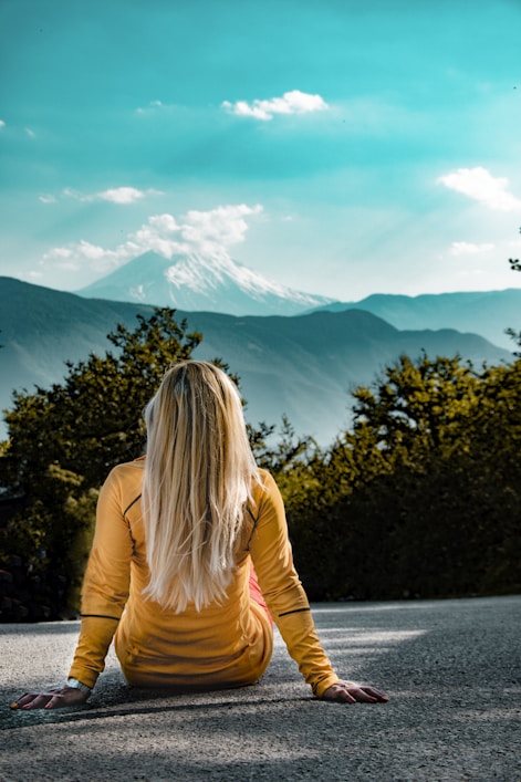 woman in orange long sleeve shirt standing near green trees during daytime