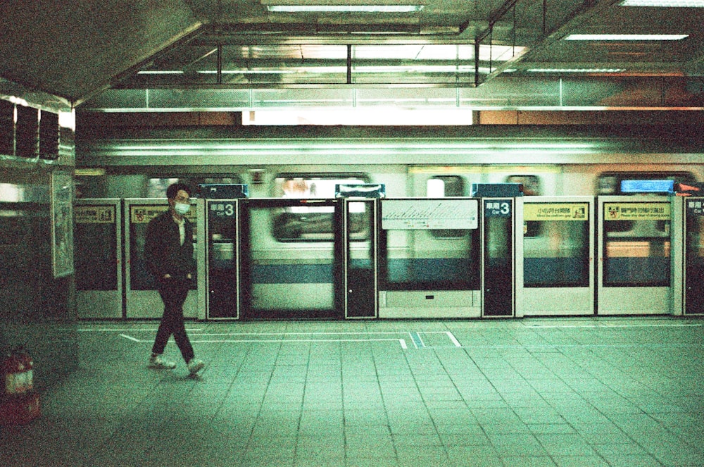 man in black jacket standing in front of train