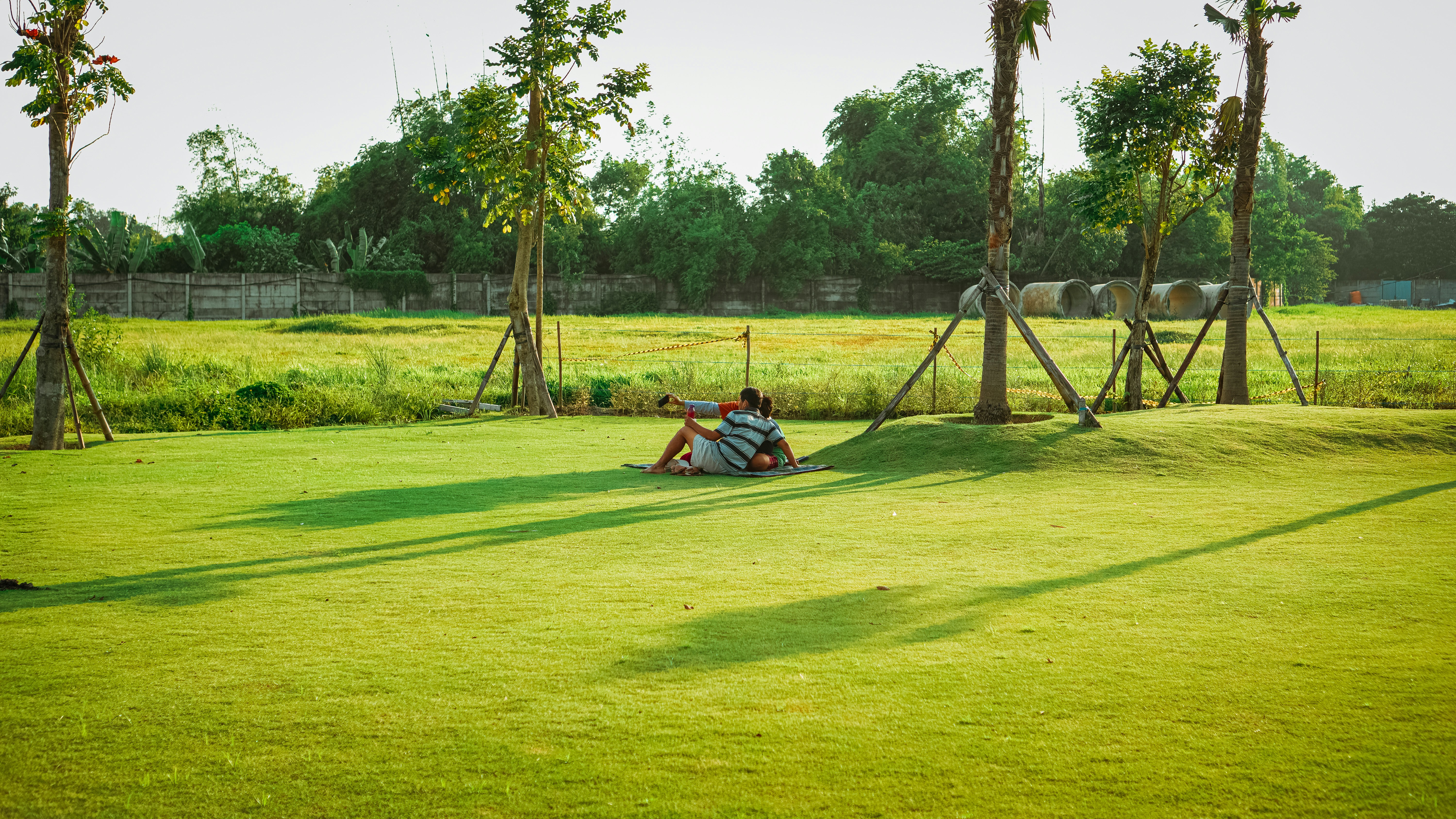 person sitting on red and black hammock on green grass field during daytime