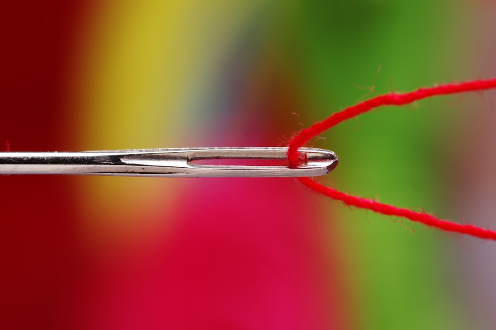 un primer plano de una aguja con un hilo rojo