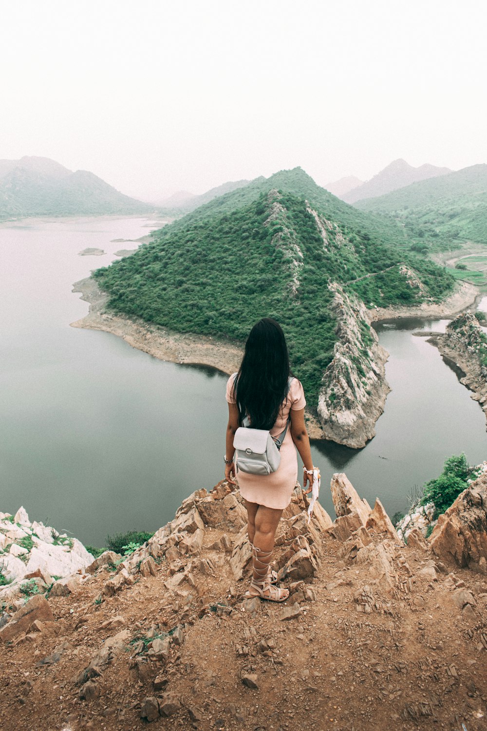 woman in white brassiere and panty sitting on rock near lake during daytime